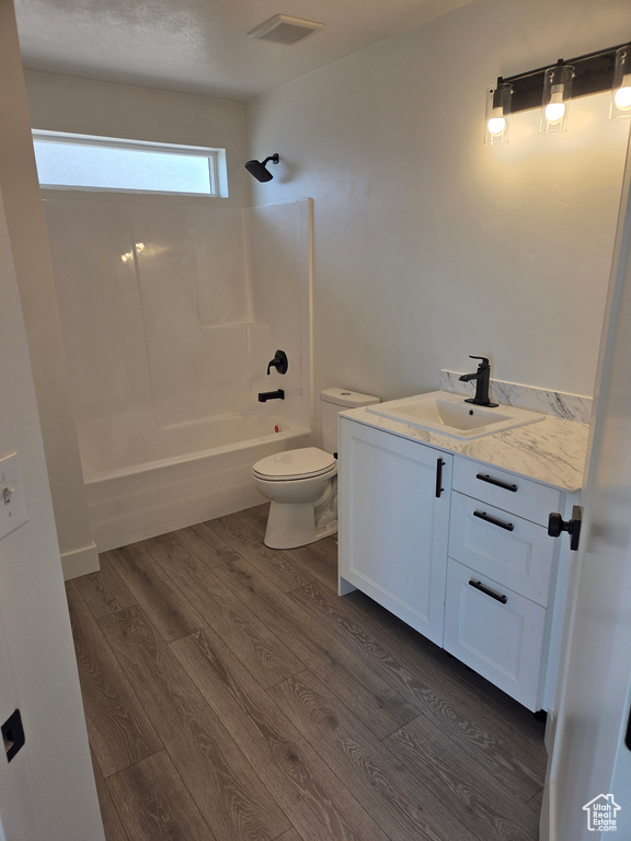 Full bath featuring toilet, vanity,  shower combination, and wood finished floors