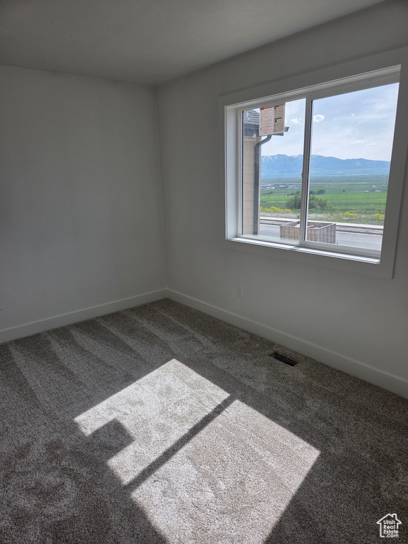 Carpeted empty room with baseboards and a mountain view