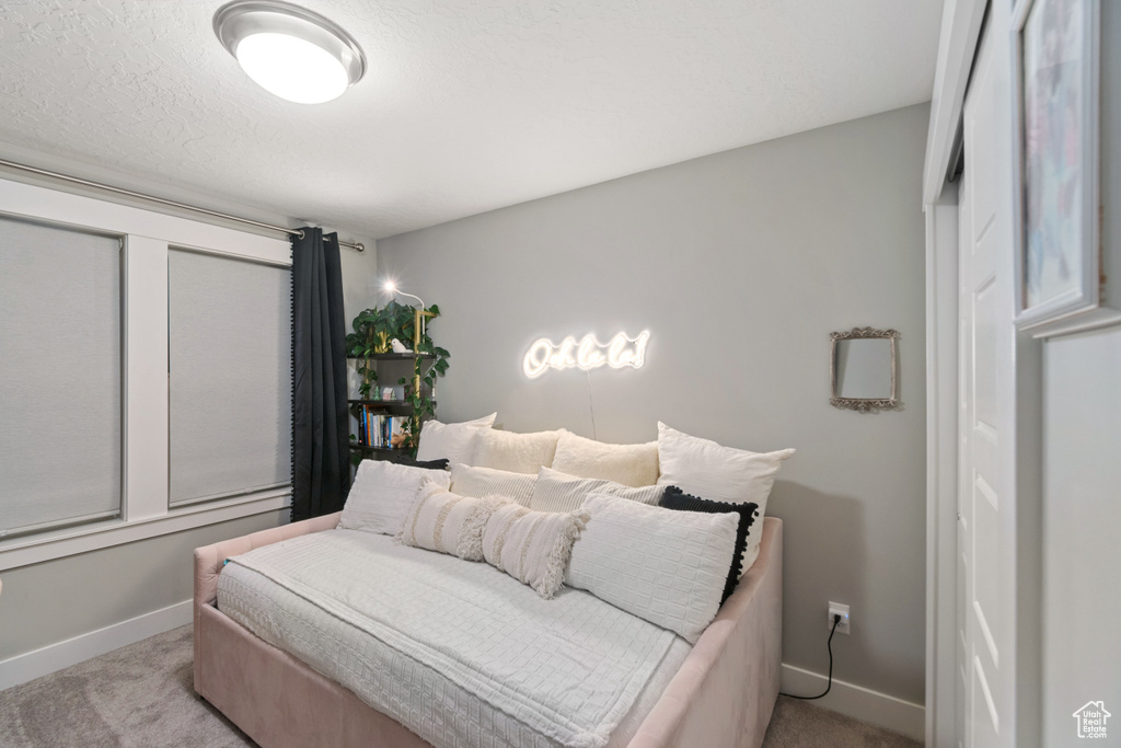 Bedroom featuring a textured ceiling and light colored carpet