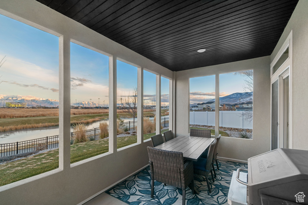 Sunroom / solarium featuring a water and mountain view