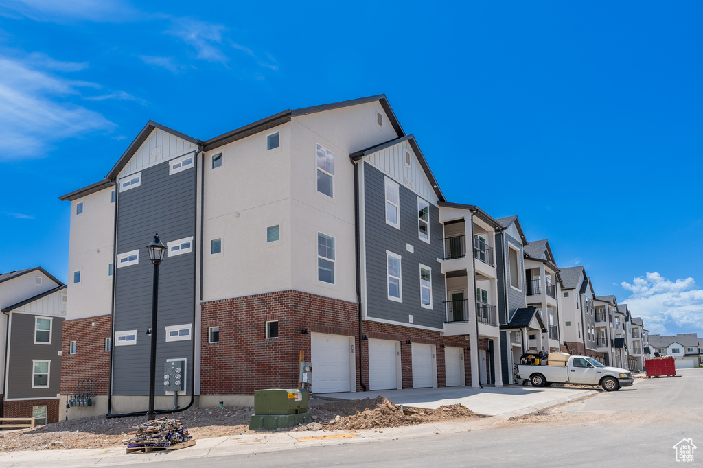 View of building exterior featuring an attached garage, a residential view, and concrete driveway