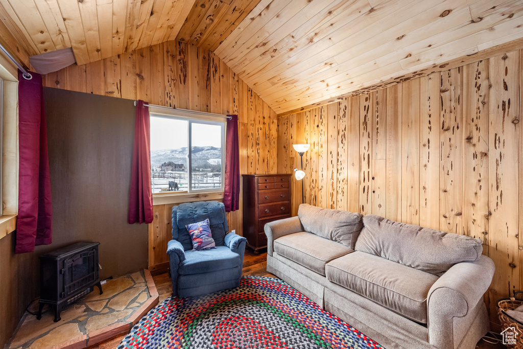 Living area with wooden ceiling, lofted ceiling, wood walls, a wood stove, and wood finished floors