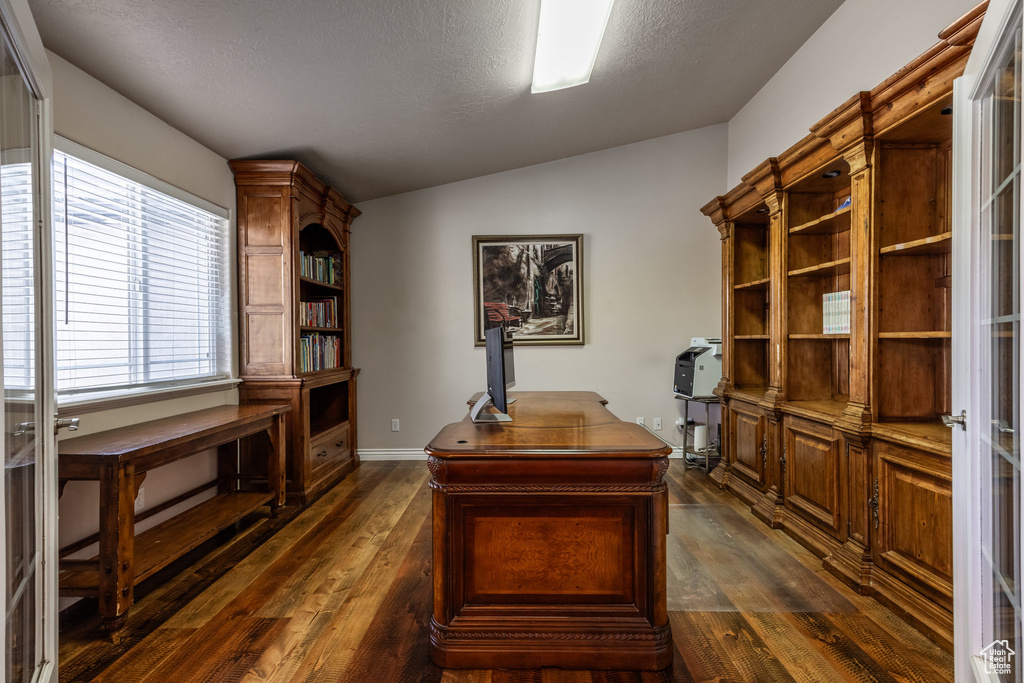 Office featuring dark wood-type flooring, lofted ceiling, baseboards, and a textured ceiling