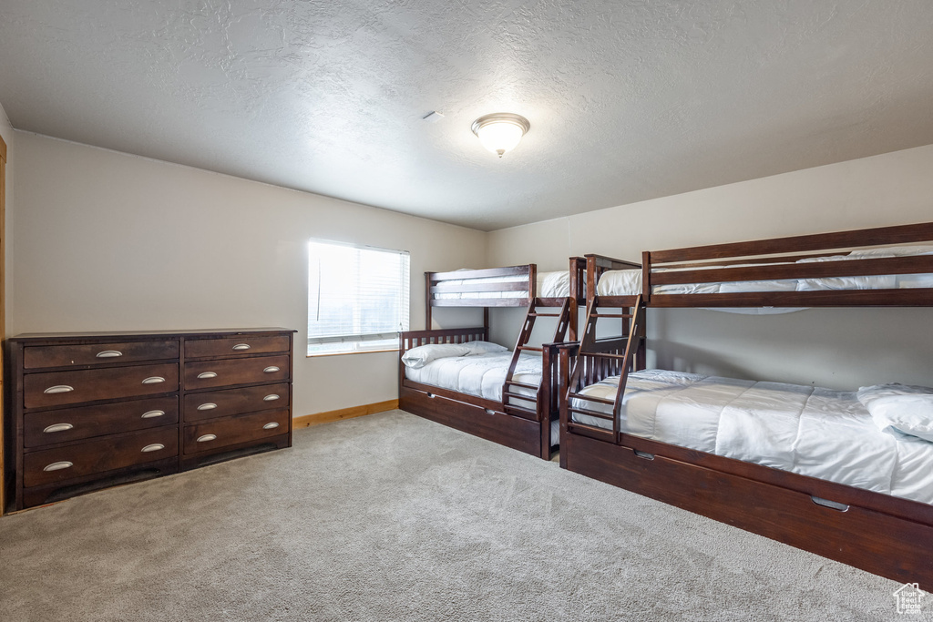 Bedroom with light carpet, baseboards, and a textured ceiling