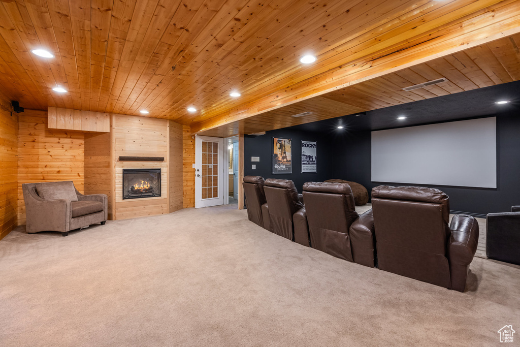 Home theater room with carpet, wooden walls, recessed lighting, wooden ceiling, and a large fireplace