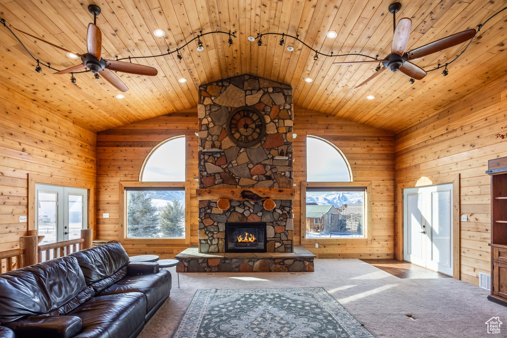 Living room with a ceiling fan, plenty of natural light, carpet floors, wood walls, and recessed lighting