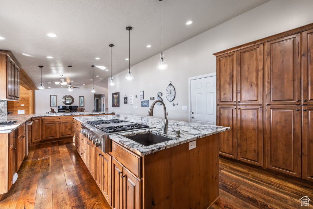 Kitchen featuring a sink, dark wood-style floors, recessed lighting, a spacious island, and light stone counters