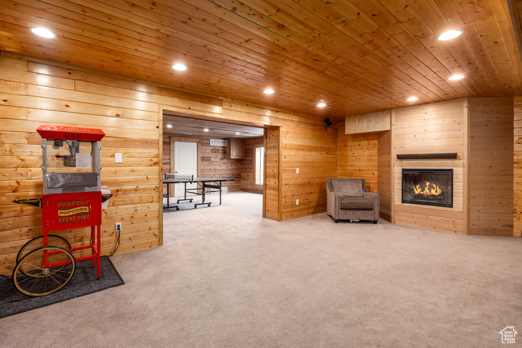 Sitting room with recessed lighting, carpet floors, wooden ceiling, wood walls, and a glass covered fireplace