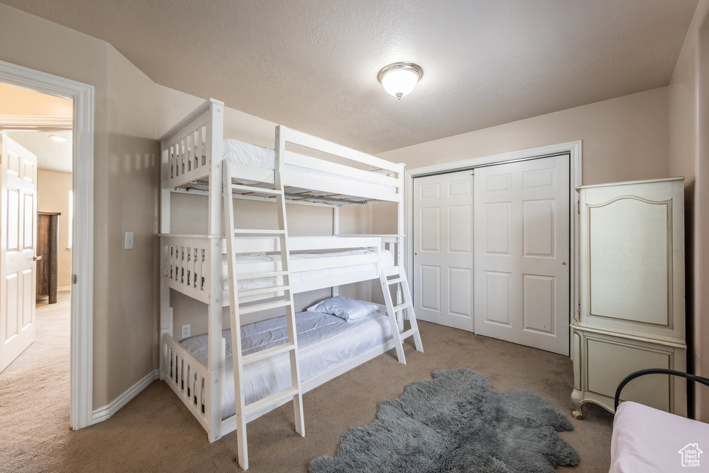 Carpeted bedroom with a closet and baseboards