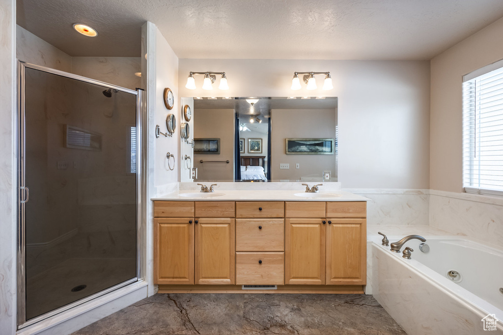 Ensuite bathroom featuring a shower stall, a jetted tub, double vanity, and a textured ceiling
