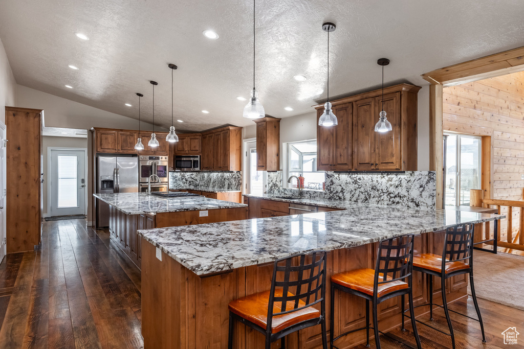 Kitchen with stainless steel appliances, brown cabinetry, a textured ceiling, decorative backsplash, and recessed lighting