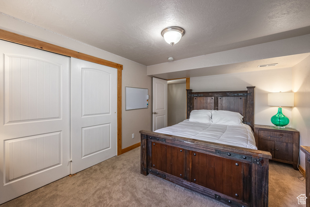 Bedroom featuring light colored carpet, a textured ceiling, and baseboards