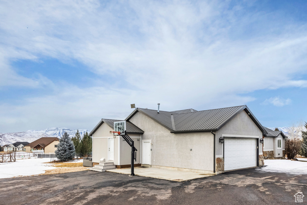 Snow covered property featuring an attached garage, metal roof, a standing seam roof, a mountain view, and fence