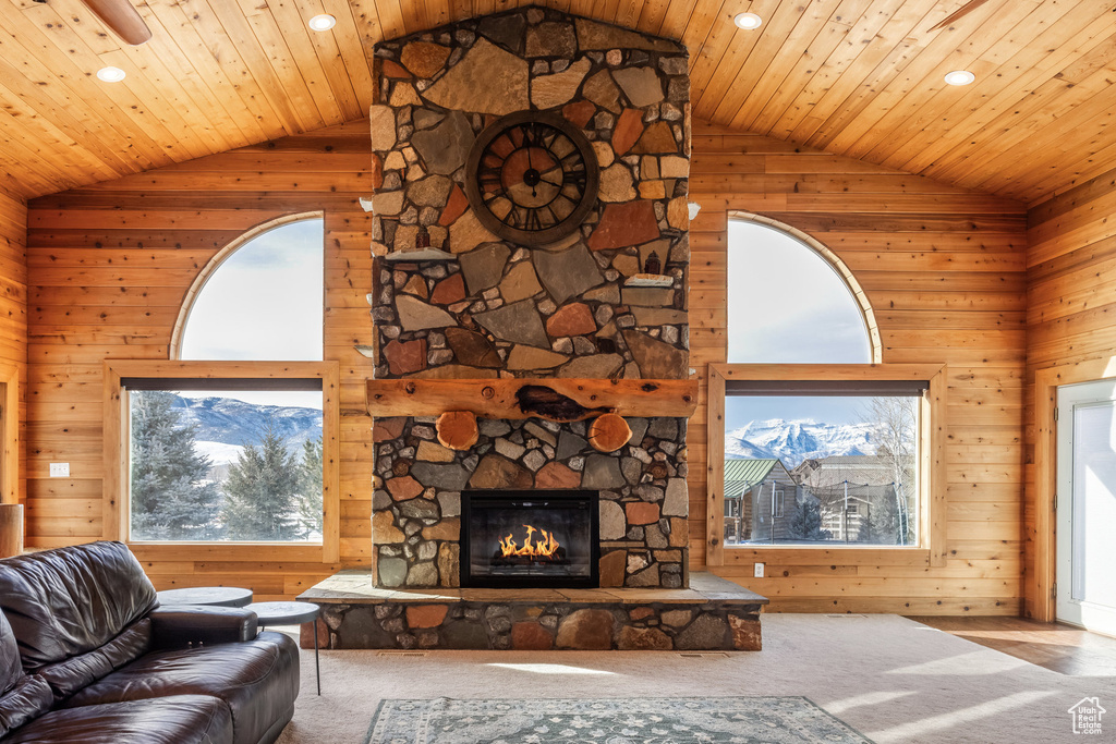 Living room with plenty of natural light, wooden walls, recessed lighting, a fireplace, and high vaulted ceiling