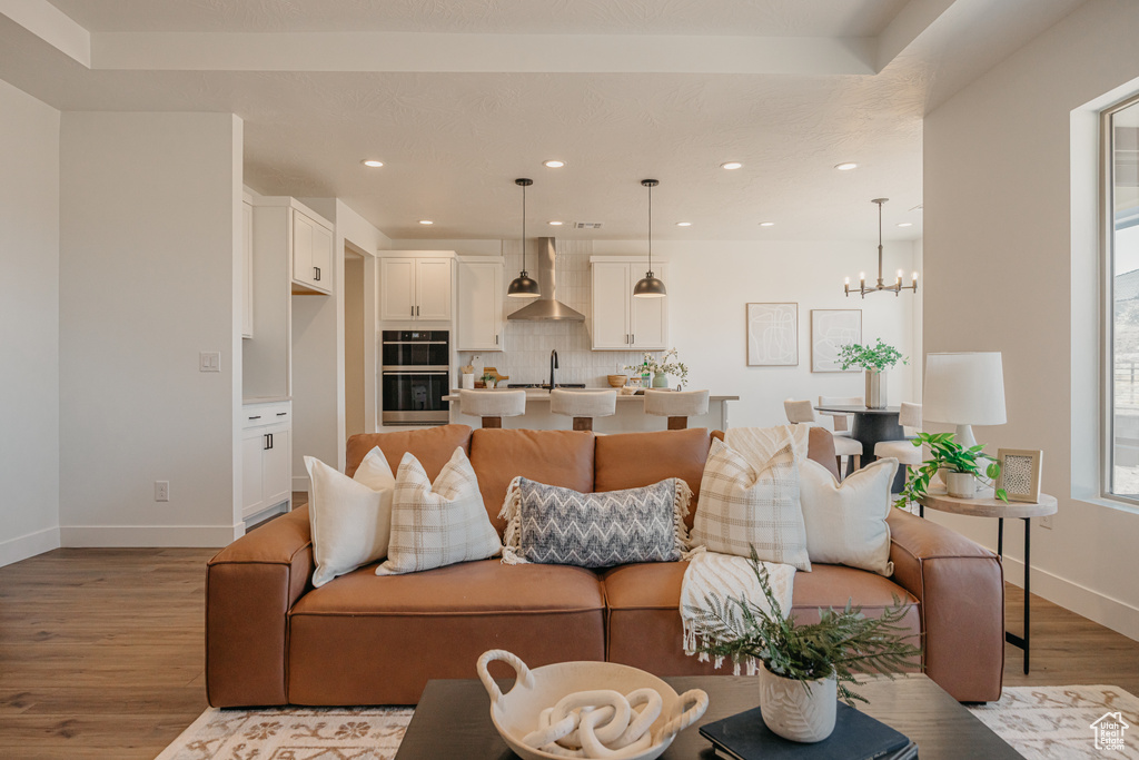 Living room with light wood-style flooring, a chandelier, and recessed lighting