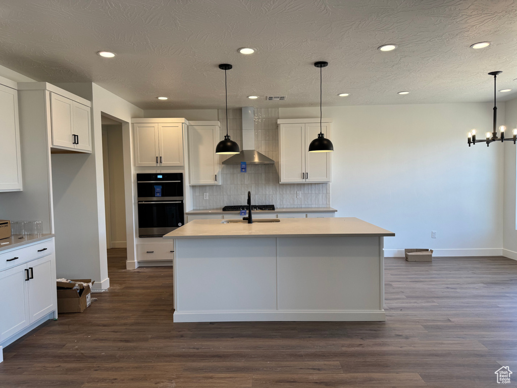 Kitchen with wall chimney exhaust hood, multiple ovens, recessed lighting, baseboards, and tasteful backsplash