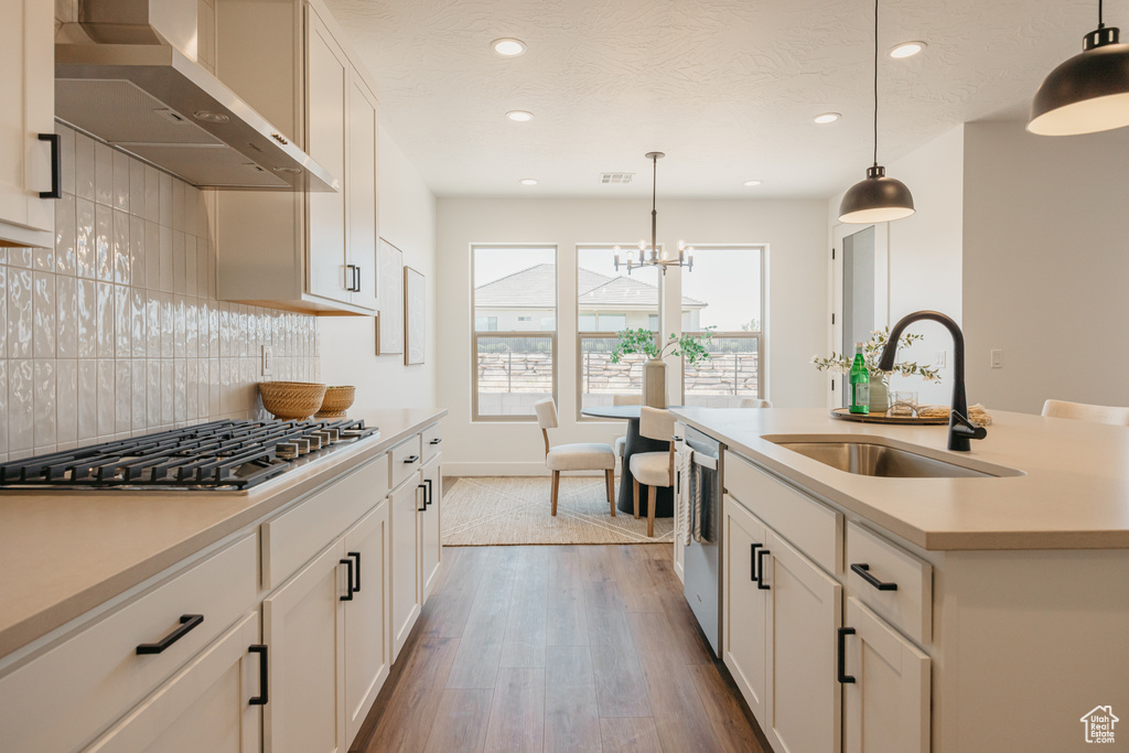 Kitchen featuring ventilation hood, stainless steel appliances, light countertops, recessed lighting, and backsplash