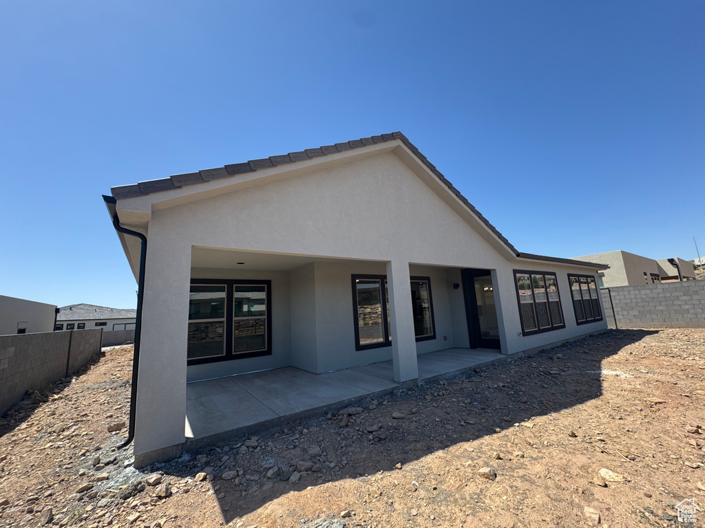 Back of property featuring a fenced backyard, a patio, and stucco siding