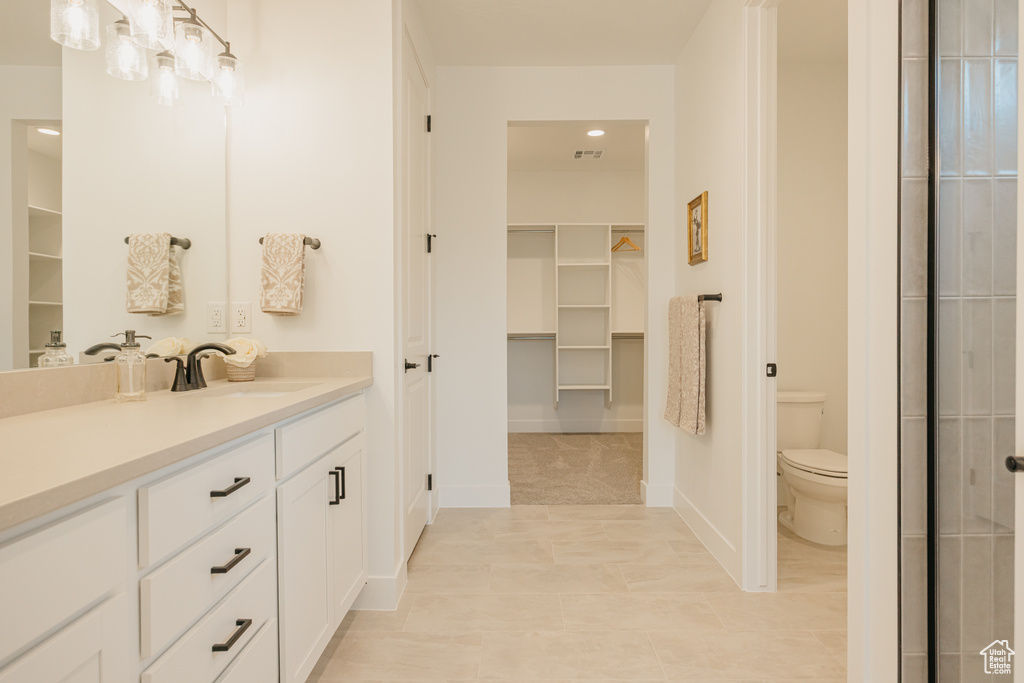 Bathroom featuring vanity, a walk in closet, tile patterned floors, and recessed lighting
