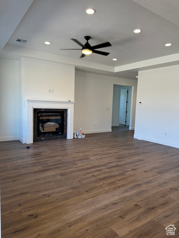 Unfurnished living room featuring baseboards, a glass covered fireplace, dark wood-type flooring, recessed lighting, and a textured ceiling
