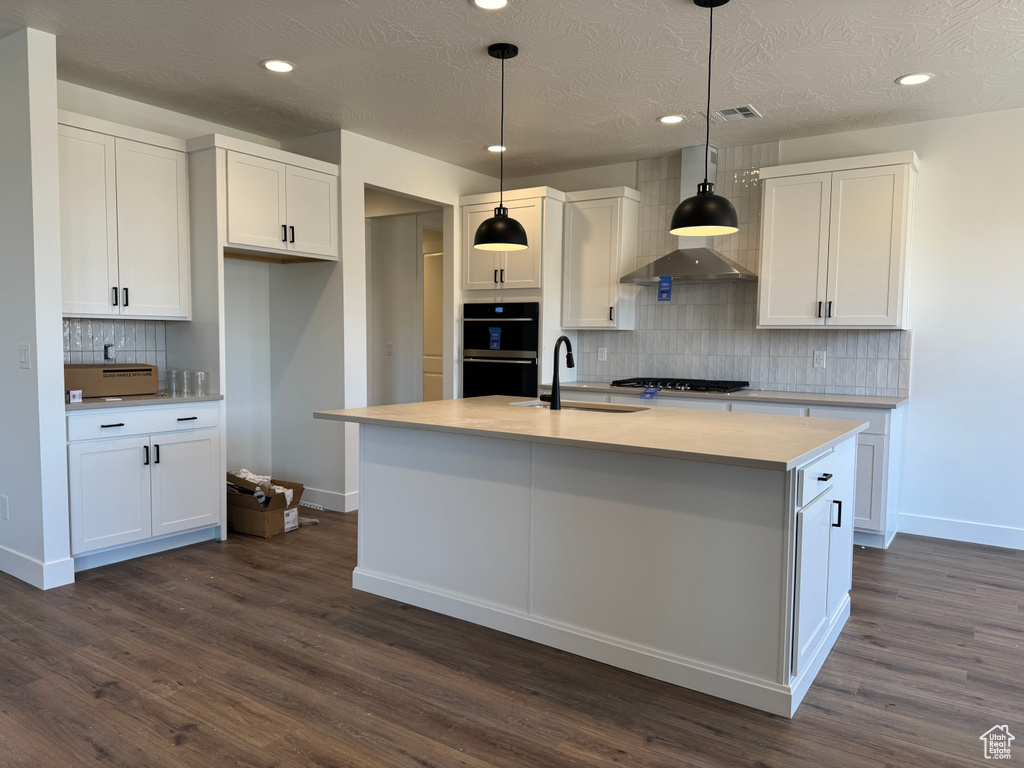 Kitchen with a sink, baseboards, backsplash, white cabinets, and gas cooktop