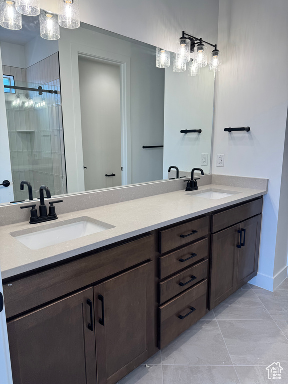 Bathroom with double vanity, a stall shower, and baseboards