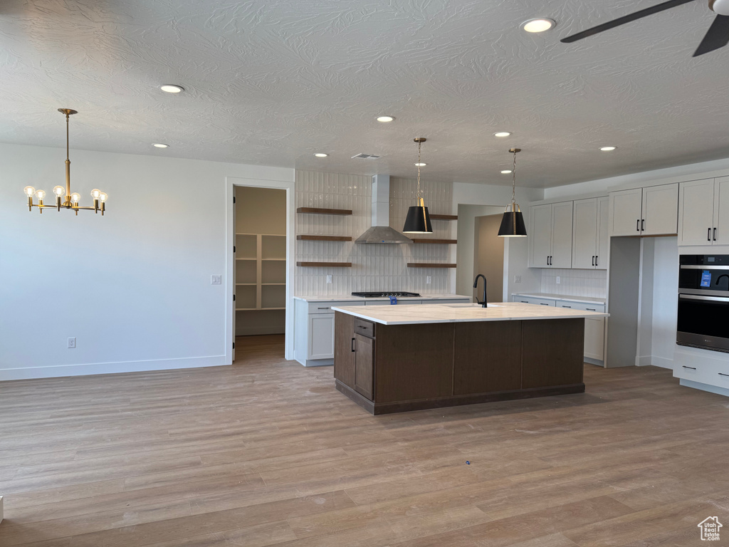 Kitchen with open shelves, wall chimney exhaust hood, recessed lighting, a chandelier, and tasteful backsplash