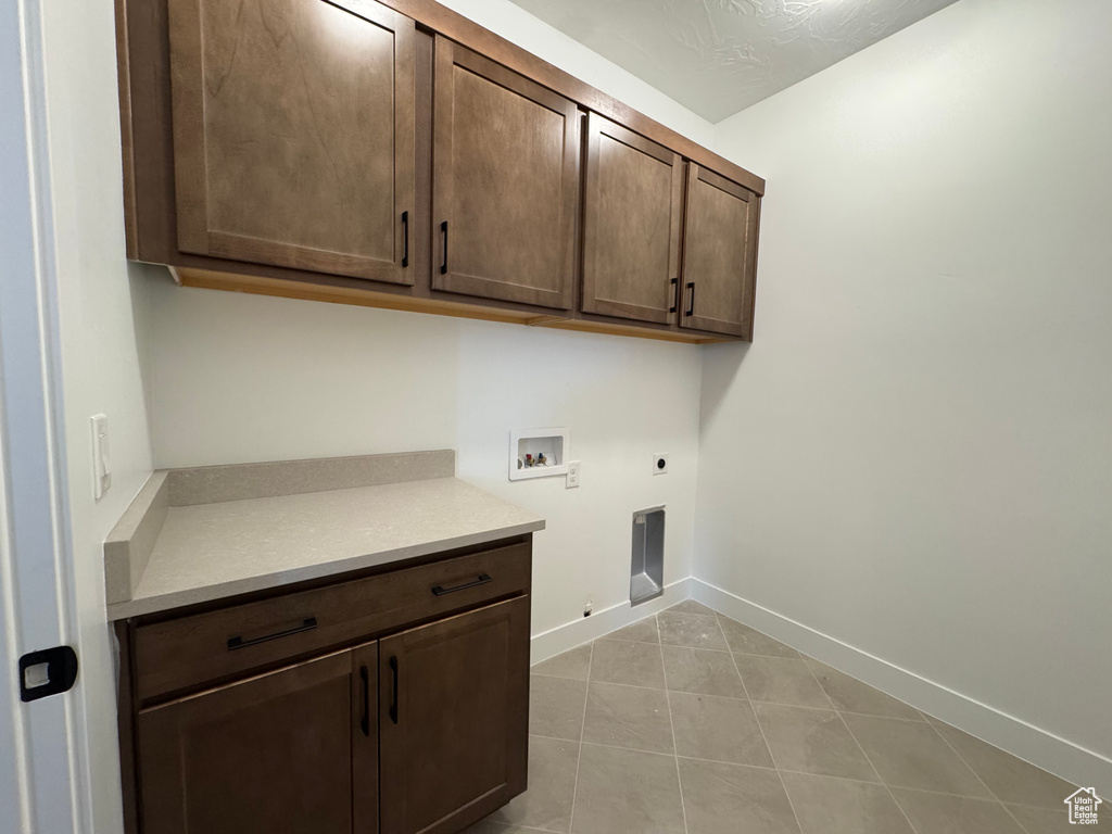 Laundry room featuring cabinet space, hookup for an electric dryer, hookup for a washing machine, light tile patterned floors, and baseboards