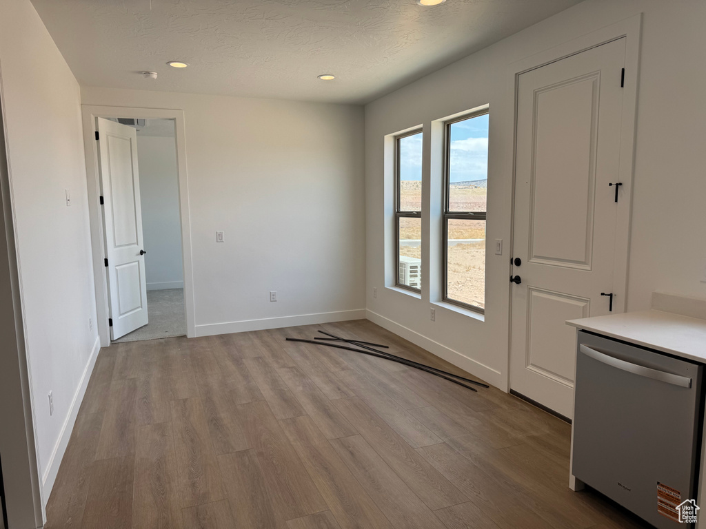 Unfurnished dining area featuring wood finished floors, recessed lighting, baseboards, and a textured ceiling