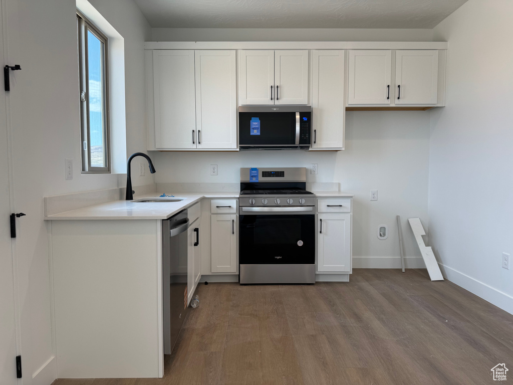 Kitchen featuring stainless steel appliances, a sink, light wood-style flooring, white cabinets, and light countertops