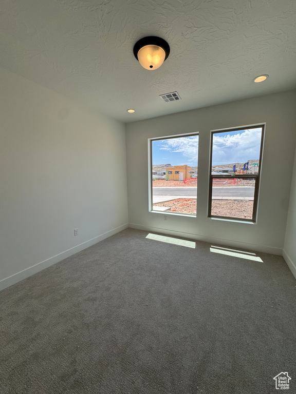 Carpeted empty room featuring a textured ceiling, baseboards, and recessed lighting