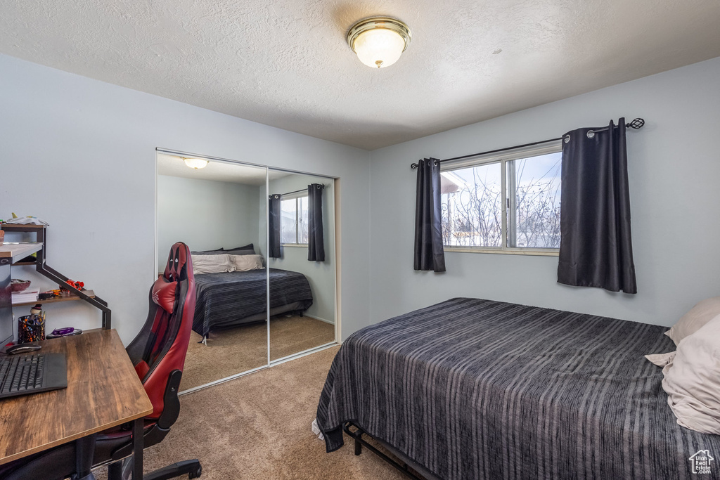 Bedroom with carpet, a closet, and a textured ceiling