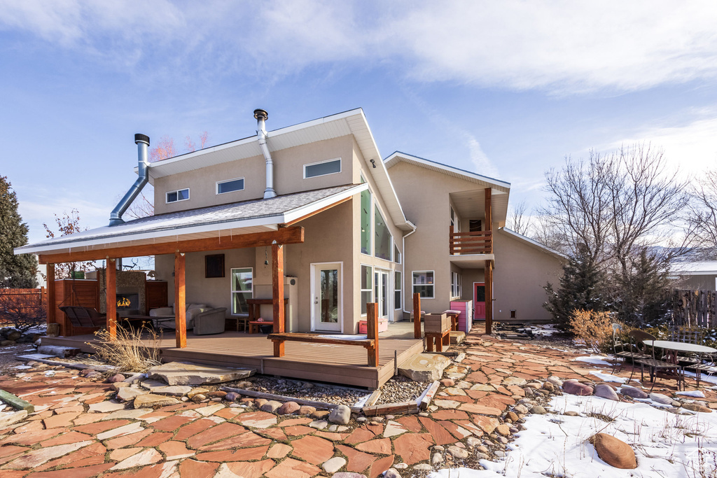 Rear view of property with stucco siding, a deck, a patio, and an outdoor fire pit