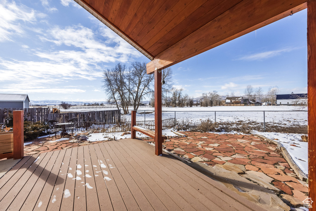 Snow covered deck with a fenced backyard