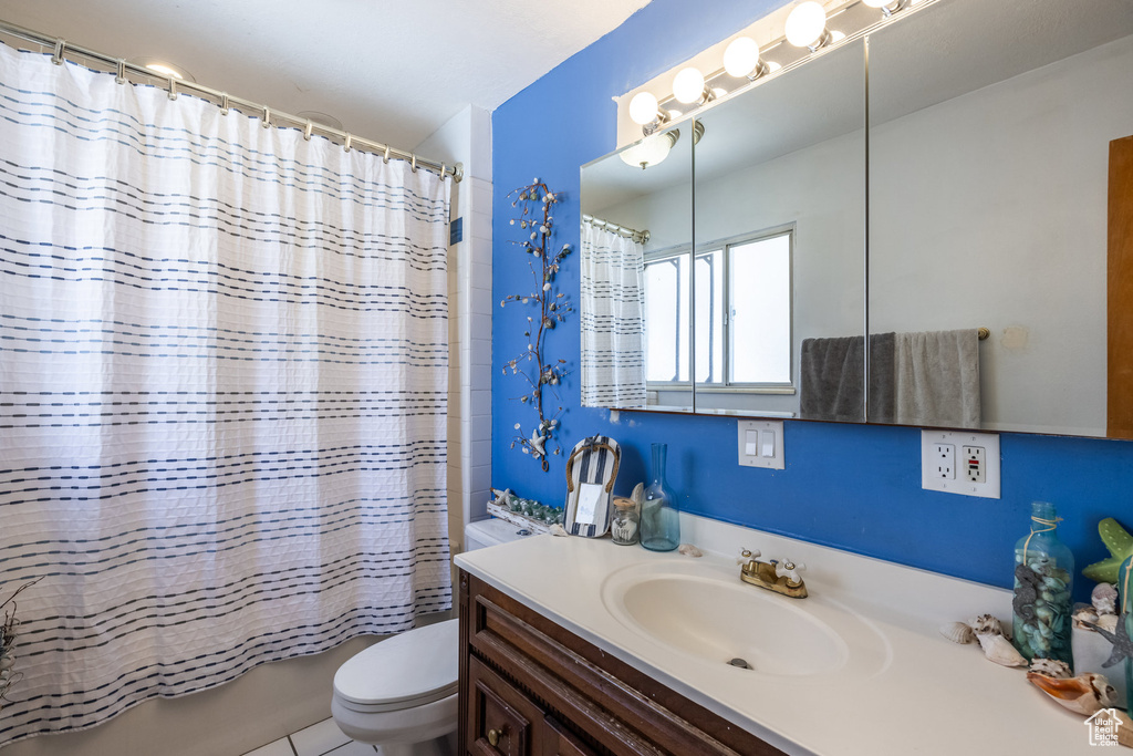 Bathroom featuring toilet, vanity, and shower / bath combination with curtain