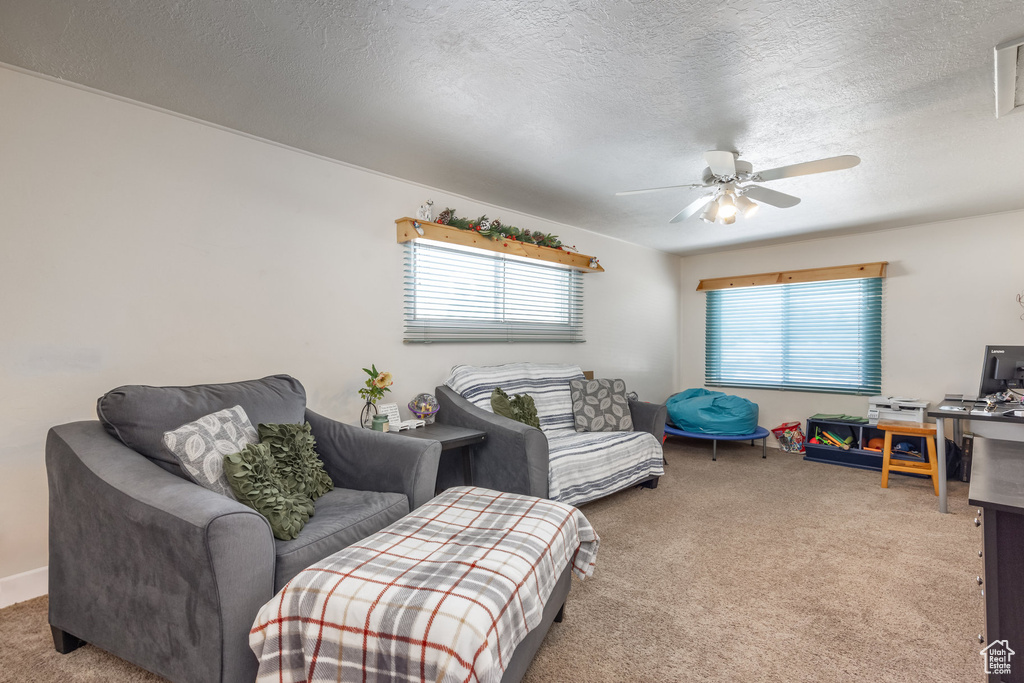 Carpeted living room with healthy amount of natural light, a ceiling fan, and a textured ceiling