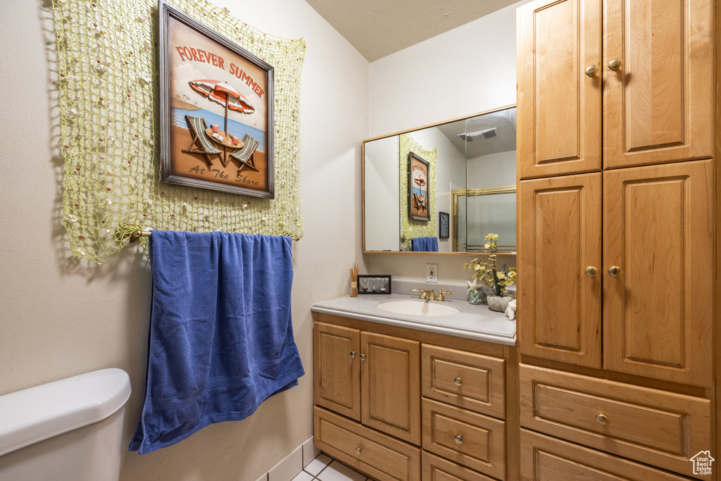 Bathroom featuring toilet, tile patterned floors, an enclosed shower, and vanity