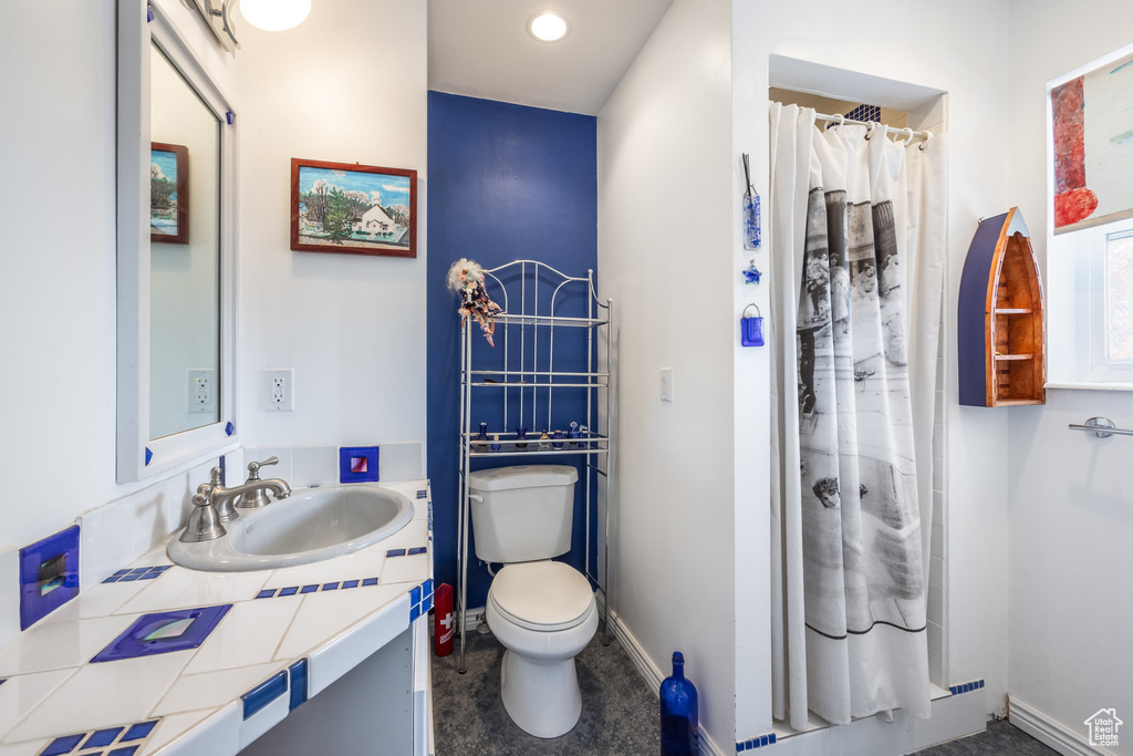 Full bath with toilet, baseboards, curtained shower, and vanity