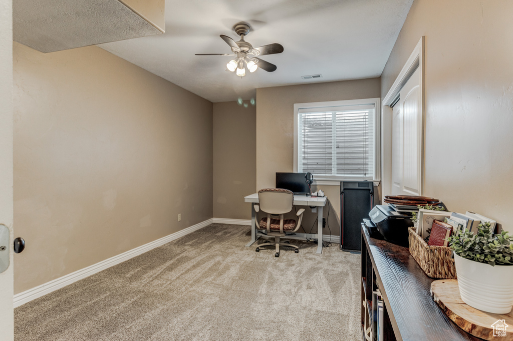 Office area featuring light carpet and a ceiling fan