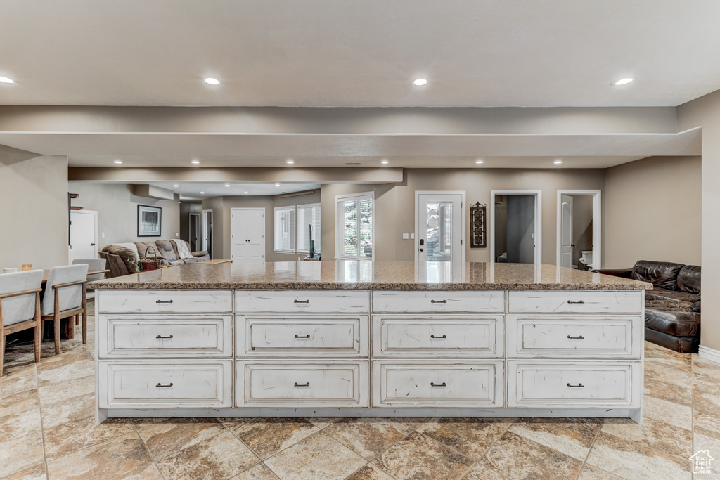 Kitchen with open floor plan, recessed lighting, light stone countertops, a center island, and white cabinets