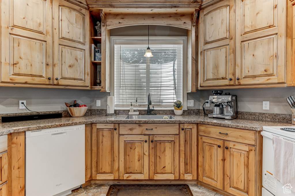 Kitchen featuring white appliances, pendant lighting, and light brown cabinets