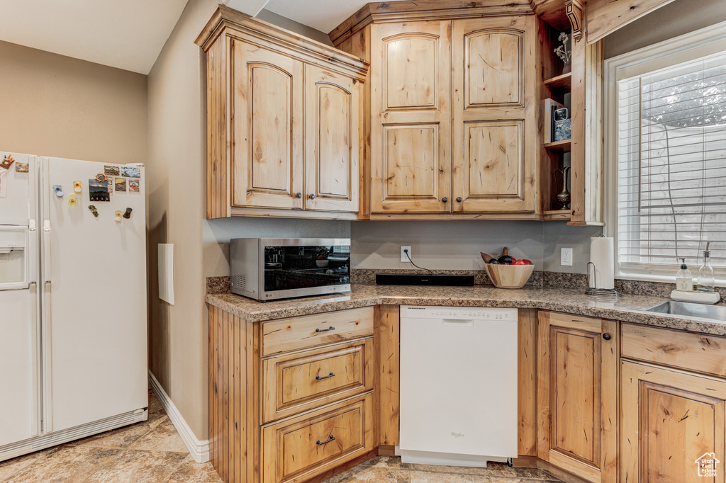 Kitchen featuring white appliances and light brown cabinets