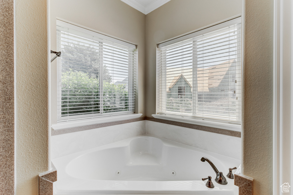 Full bath featuring a tub with jets, a textured wall, and ornamental molding