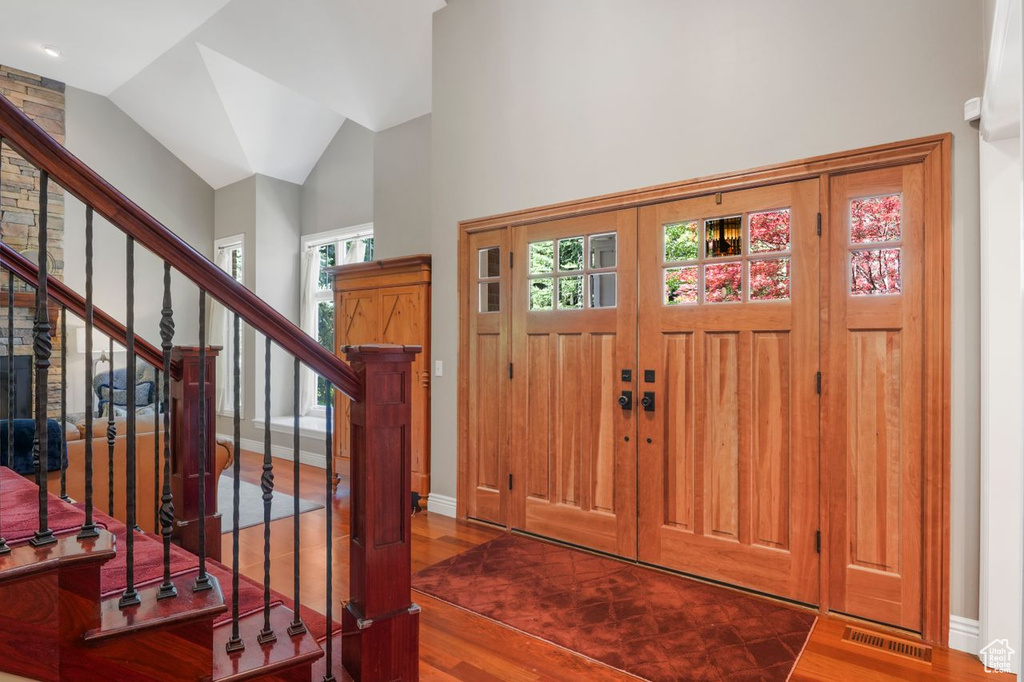 Foyer with high vaulted ceiling and wood-type flooring