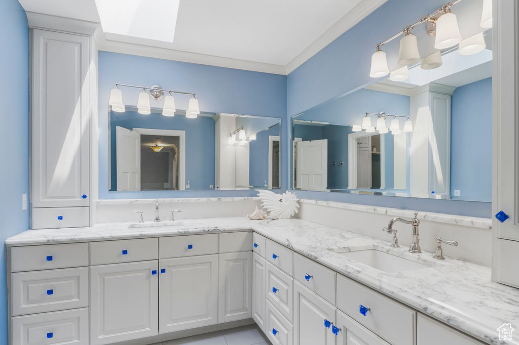 Bathroom with tile patterned floors, ornamental molding, a skylight, and vanity