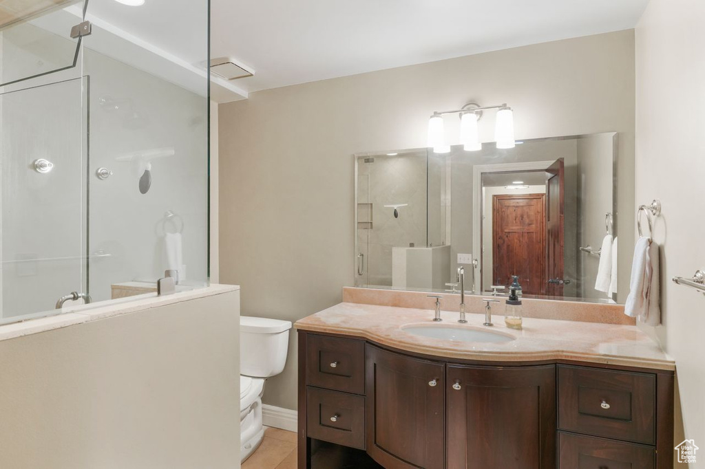 Bathroom with tile patterned floors, toilet, a shower with door, and vanity