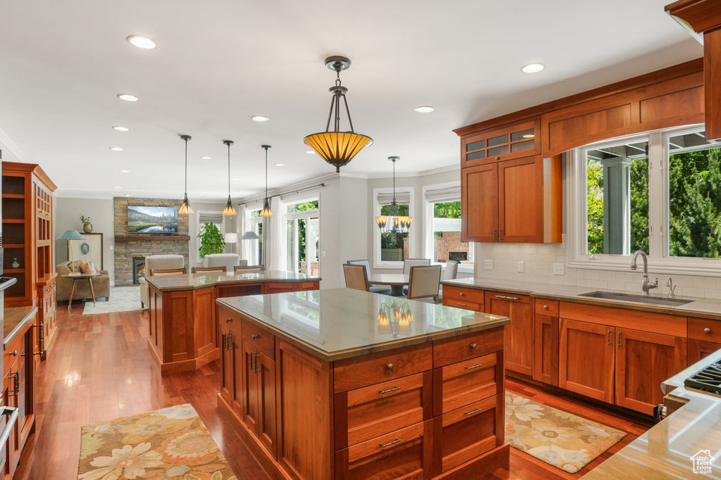 Kitchen with hanging light fixtures, a center island, sink, tasteful backsplash, and crown molding
