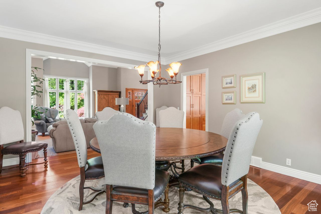 Dining room featuring an inviting chandelier, crown molding, and dark hardwood / wood-style floors