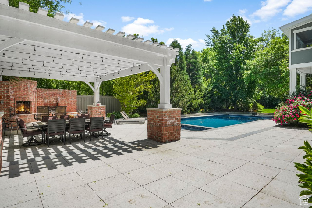 View of patio featuring an outdoor brick fireplace and a pergola