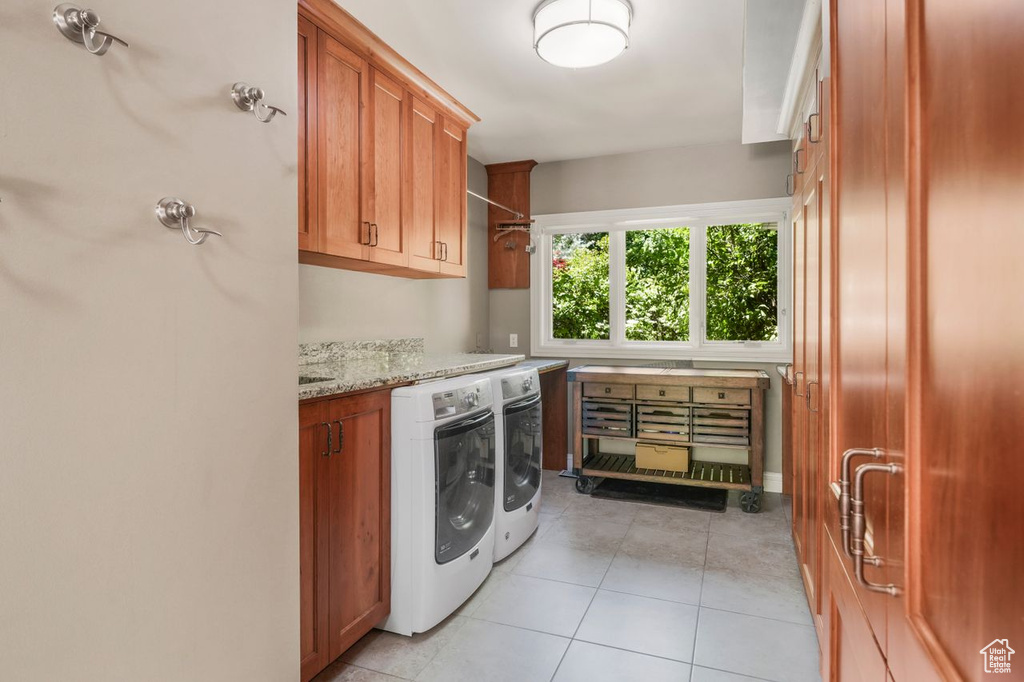 Washroom with cabinets, washer and clothes dryer, and light tile patterned floors